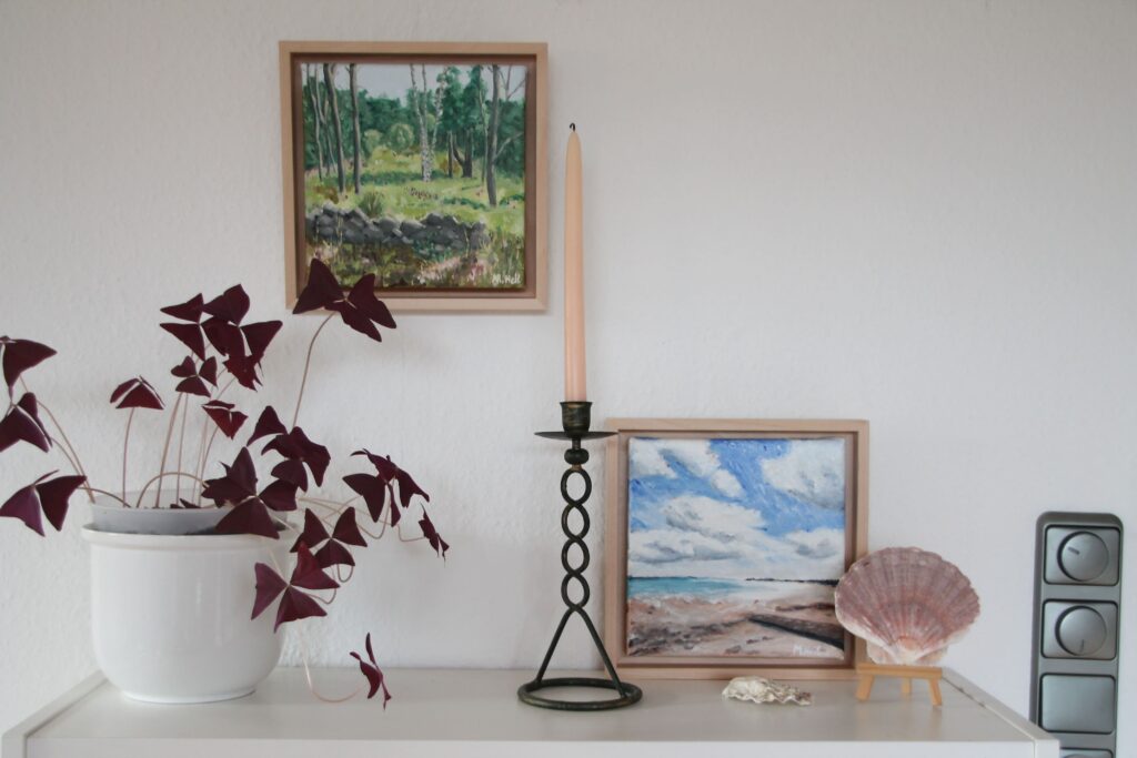 styling original artworks on a book shelf with decoration pieces and plants that match the colours