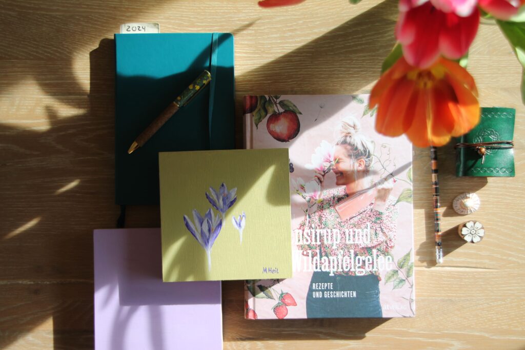 a painted crocus on wood panel surrounded by flowery books and journals